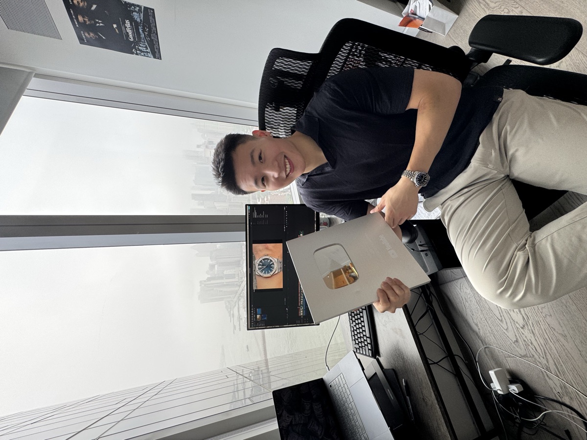 Justin Zhou with a YouTube Silver Play Button award, New York skyline behind him