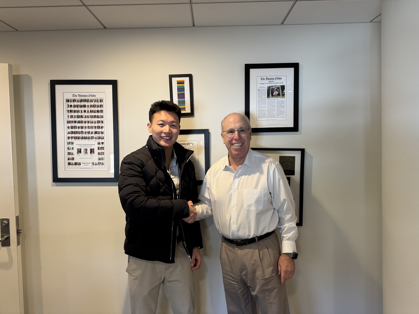 Justin Zhou shaking hands with a Babson College executive